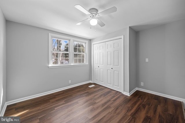 unfurnished bedroom featuring dark wood-type flooring, ceiling fan, and a closet