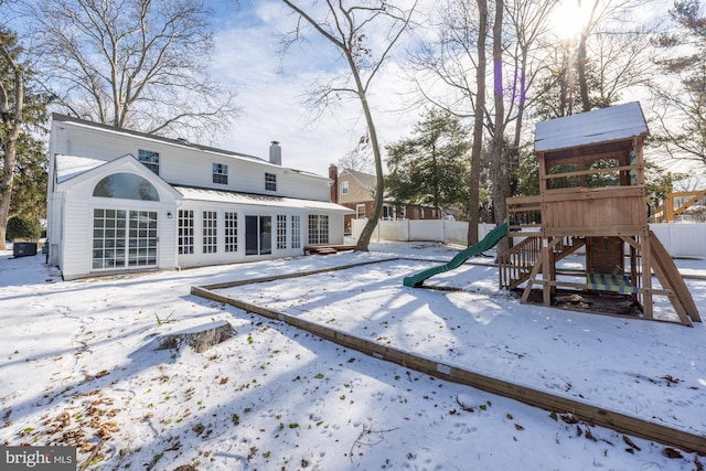 snow covered house with a playground and french doors