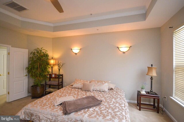 carpeted bedroom with crown molding and a tray ceiling