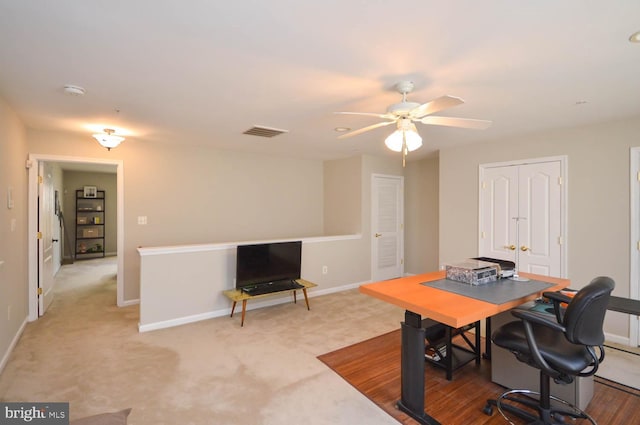 carpeted office space with ceiling fan