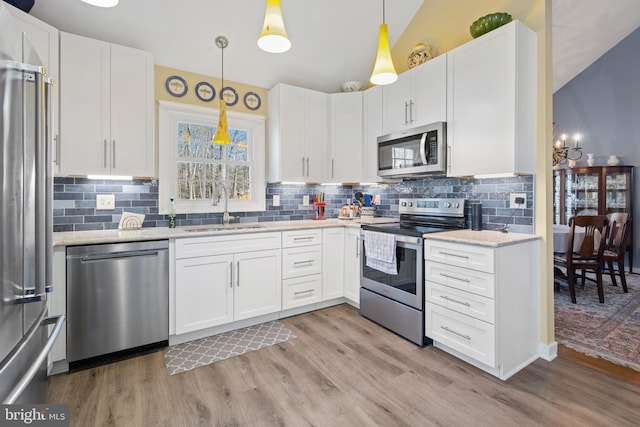 kitchen featuring stainless steel appliances, white cabinetry, sink, and pendant lighting