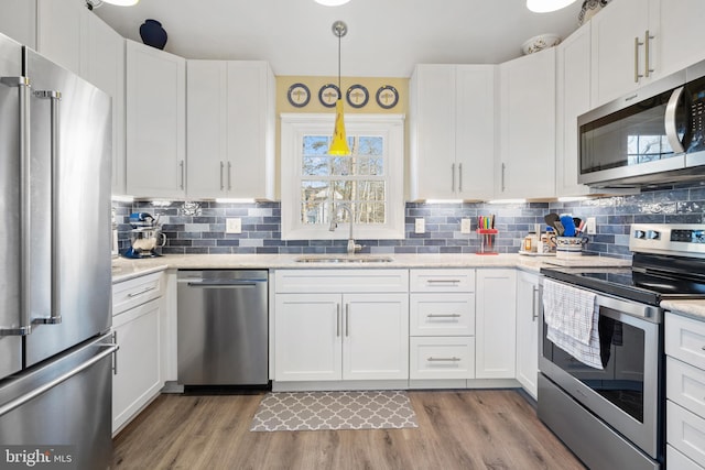 kitchen with sink, white cabinetry, tasteful backsplash, hanging light fixtures, and appliances with stainless steel finishes