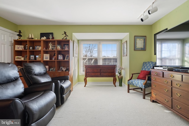 sitting room with rail lighting and light carpet