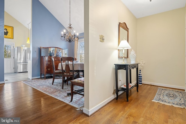 interior space with a notable chandelier, vaulted ceiling, and wood-type flooring