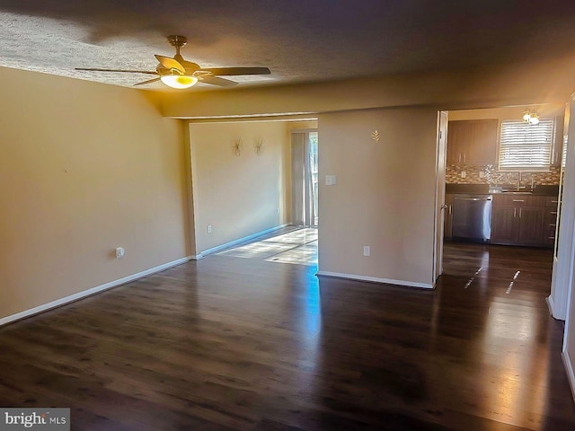 empty room with ceiling fan, dark hardwood / wood-style flooring, and a textured ceiling