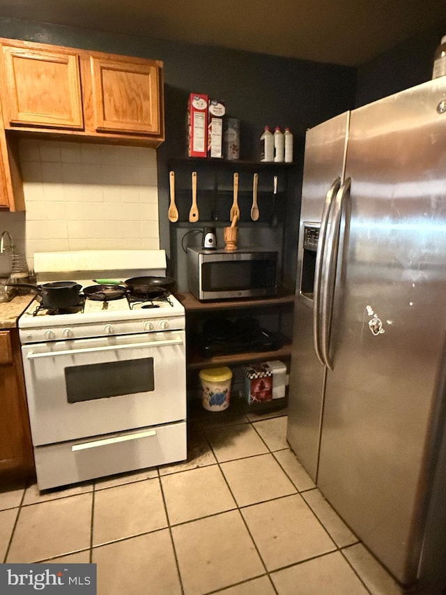 kitchen featuring appliances with stainless steel finishes, light tile patterned floors, and backsplash