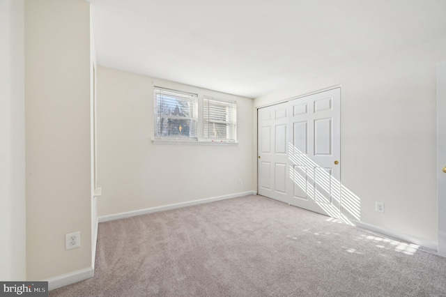 unfurnished bedroom with light colored carpet and a closet