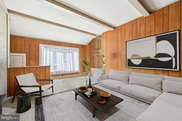 carpeted living room with wooden walls and lofted ceiling with beams