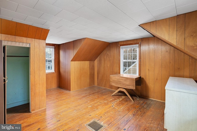 bonus room with plenty of natural light, light hardwood / wood-style floors, and wood walls