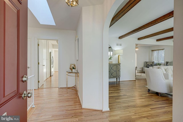 foyer entrance featuring arched walkways, visible vents, light wood-style flooring, and a skylight