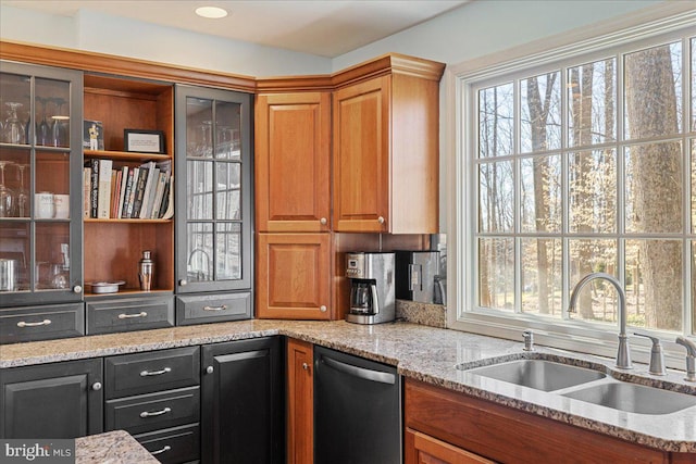 kitchen with stainless steel dishwasher, light stone countertops, and sink