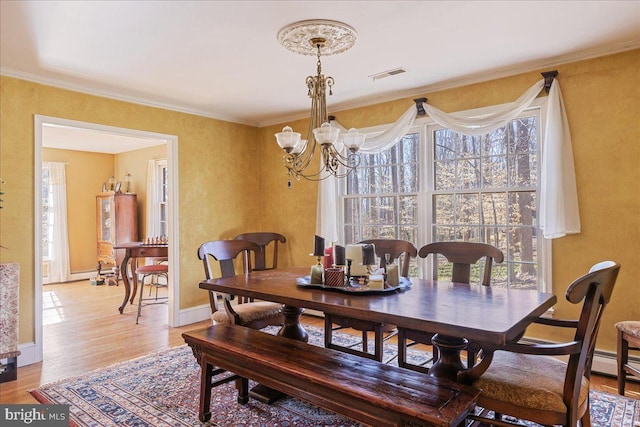 dining room with crown molding, wood-type flooring, and a chandelier