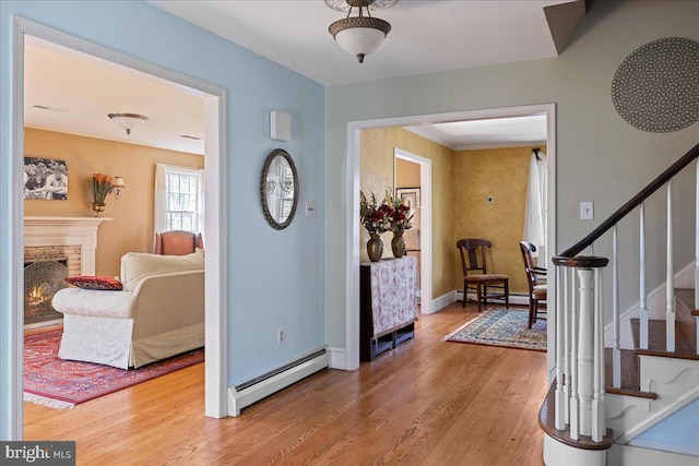 entryway featuring baseboard heating, wood-type flooring, and a brick fireplace