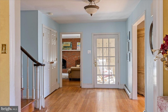 entryway featuring light hardwood / wood-style flooring, a brick fireplace, a baseboard radiator, and plenty of natural light