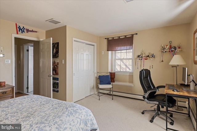 carpeted bedroom featuring a baseboard heating unit and a closet