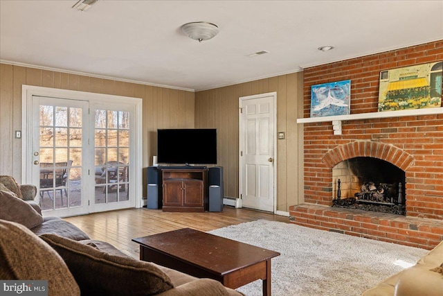 living room featuring a fireplace, crown molding, a baseboard radiator, and light hardwood / wood-style floors