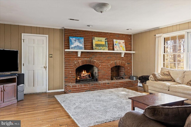 living room featuring crown molding, a fireplace, and light hardwood / wood-style flooring