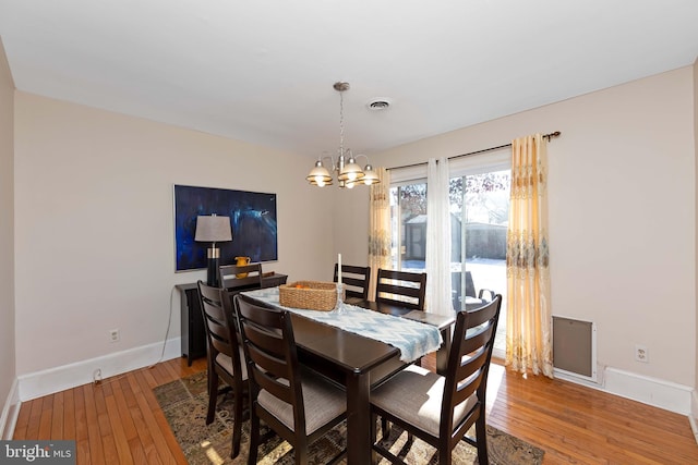 dining room with hardwood / wood-style floors and a notable chandelier