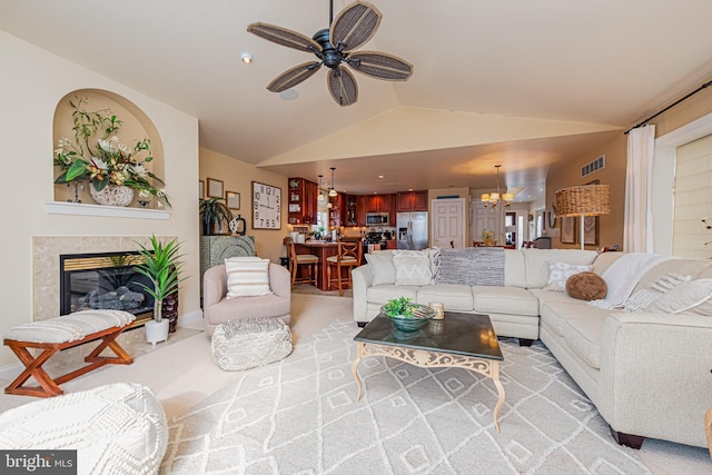 living room featuring ceiling fan with notable chandelier, light colored carpet, and vaulted ceiling