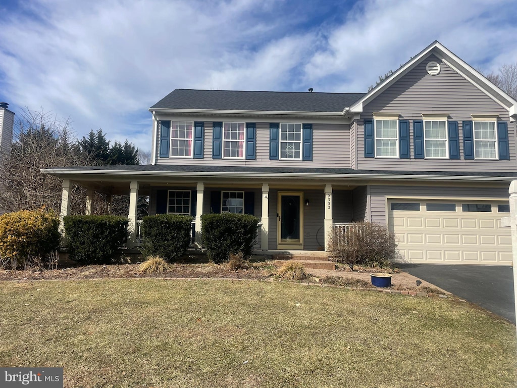 view of front of home featuring a garage, a front yard, and covered porch