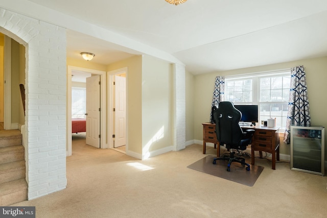 carpeted home office with vaulted ceiling