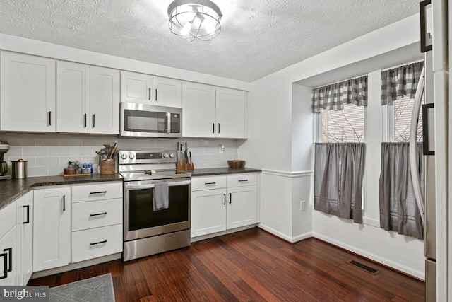 kitchen featuring appliances with stainless steel finishes, white cabinets, visible vents, and dark wood-style floors