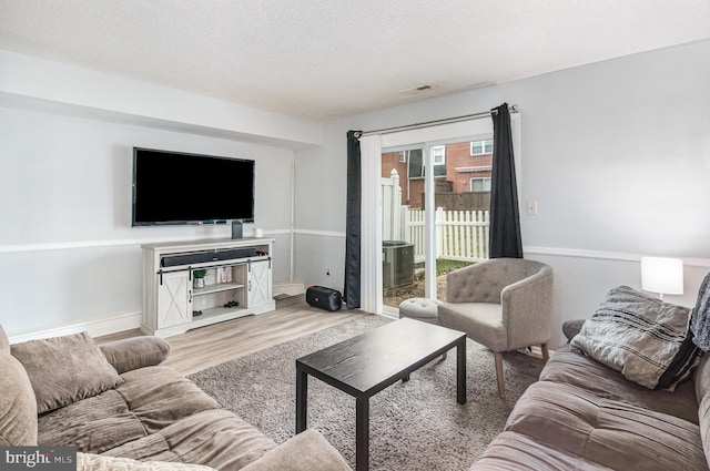 living room with light hardwood / wood-style floors and a textured ceiling