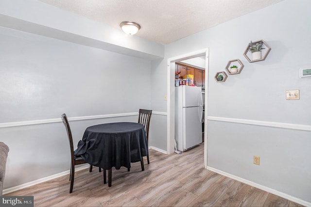 dining room with a textured ceiling and light hardwood / wood-style flooring