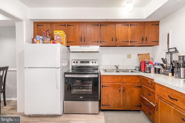 kitchen featuring white refrigerator, stainless steel electric range oven, sink, and light wood-type flooring