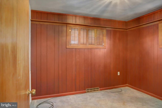 carpeted empty room featuring wooden walls