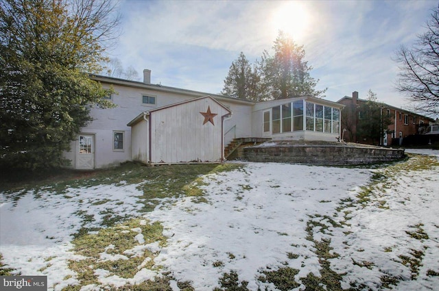 snow covered house featuring a sunroom