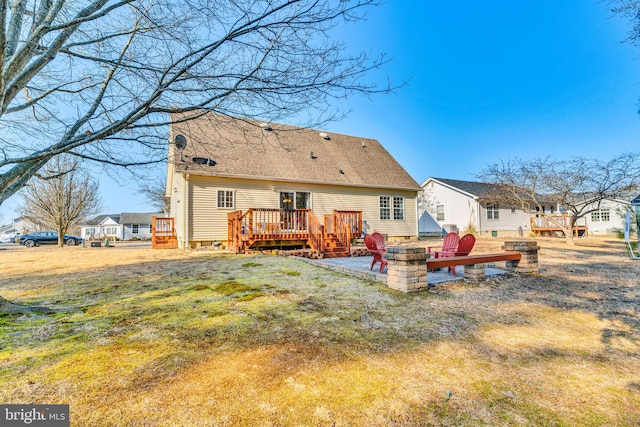 rear view of property with a wooden deck, an outdoor fire pit, and a yard