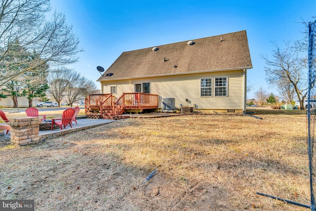 back of property featuring a lawn, a fire pit, a wooden deck, central AC unit, and a patio area