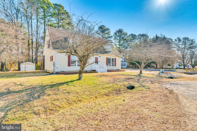 new england style home featuring a front lawn and a storage shed