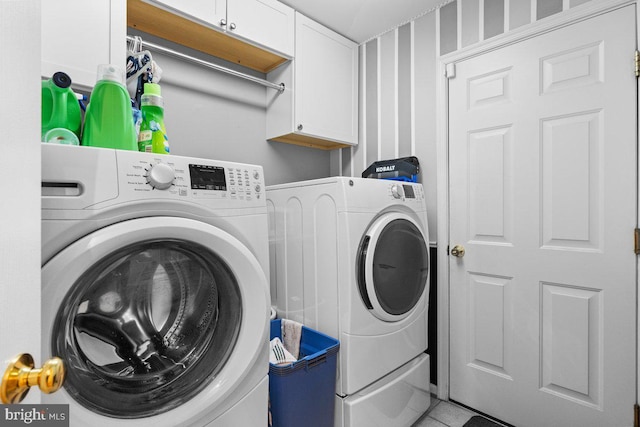 washroom featuring cabinets, light tile patterned flooring, and washing machine and clothes dryer