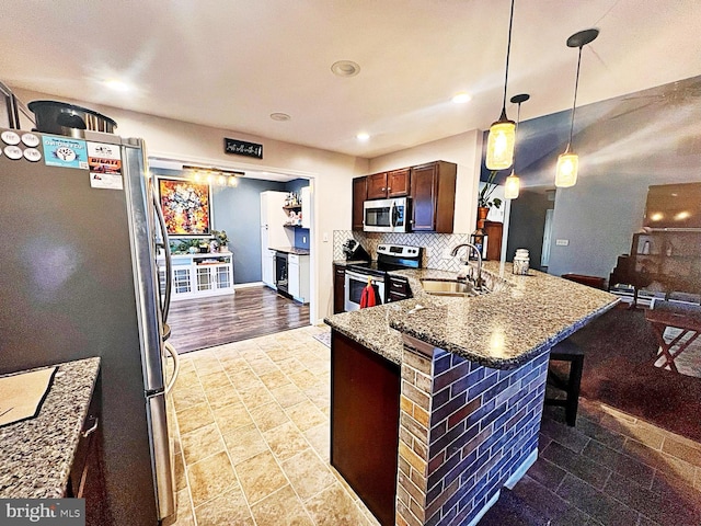 kitchen featuring appliances with stainless steel finishes, a breakfast bar, sink, hanging light fixtures, and kitchen peninsula