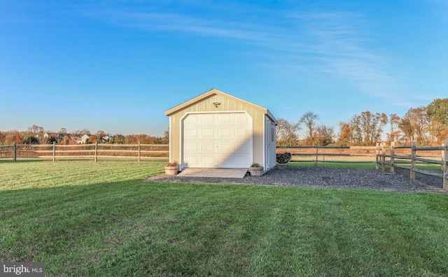 garage with a rural view and a lawn