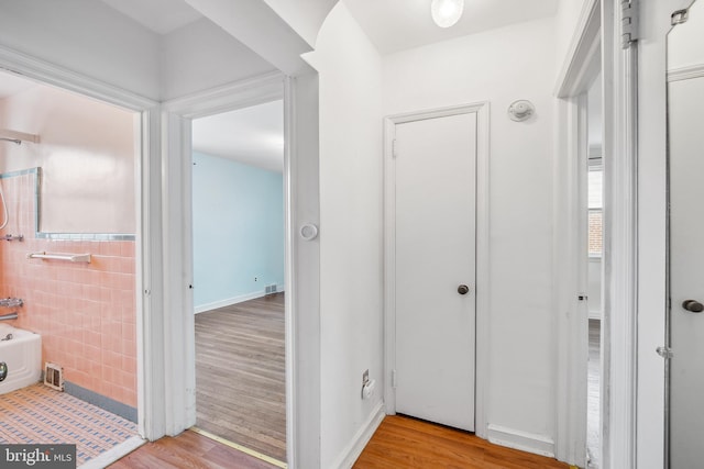 corridor with tile walls and light wood-type flooring