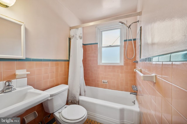 full bathroom featuring toilet, shower / bathtub combination with curtain, sink, and tile walls