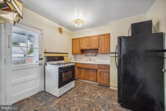 kitchen featuring black refrigerator, white gas range, and sink