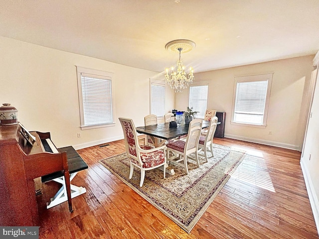 dining area featuring wood-type flooring, a chandelier, and baseboards