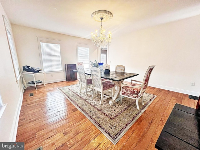 dining space featuring light wood-style floors, a wealth of natural light, a notable chandelier, and baseboards