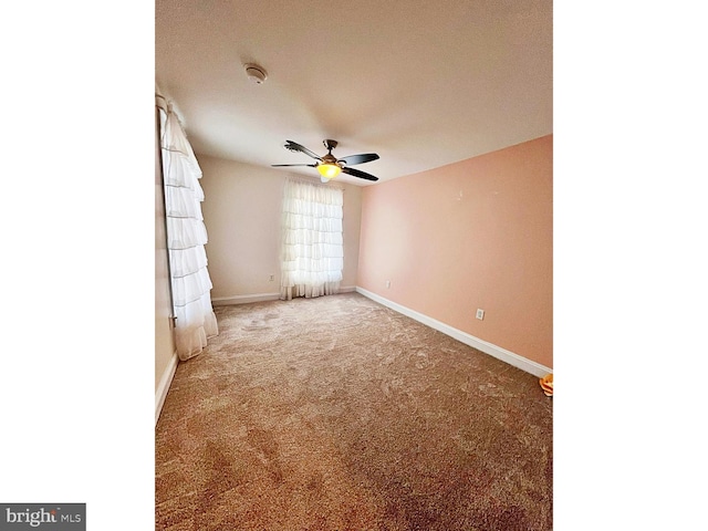 unfurnished room featuring a ceiling fan, light colored carpet, and baseboards