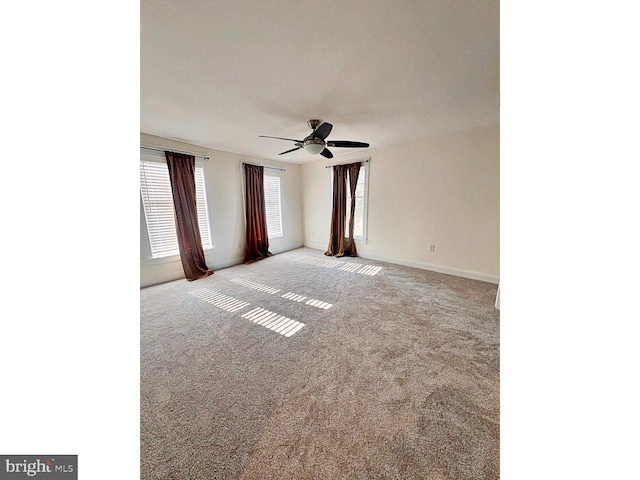 carpeted spare room featuring ceiling fan and baseboards