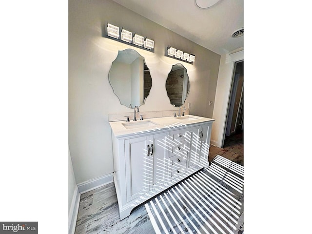 bathroom featuring double vanity, baseboards, visible vents, and a sink