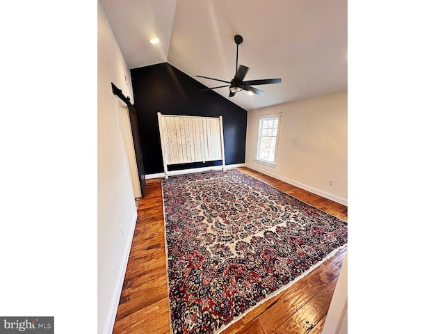 empty room featuring vaulted ceiling, ceiling fan, wood finished floors, and baseboards