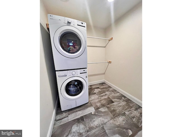 laundry area featuring stacked washer and dryer, laundry area, and baseboards