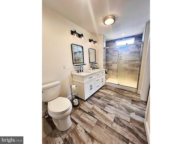 bathroom featuring toilet, a sink, baseboards, a shower stall, and double vanity