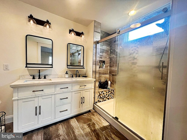 full bathroom featuring double vanity, wood finished floors, a sink, and a shower stall