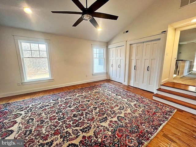 bedroom featuring visible vents, vaulted ceiling, two closets, and wood finished floors